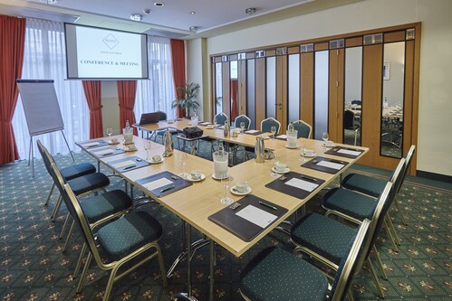 Konferenzraum mit U-f&ouml;rmig gestelltem Tisch und Pr&auml;sentationstechnik. 